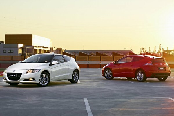 White and red Honda on the background of a city sunset