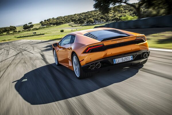 Ein orangefarbener Lamborghini rast über die Strecke