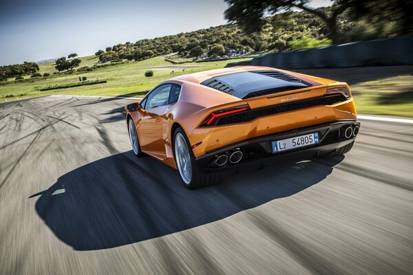 Lamborghini de color naranja corre por la pista