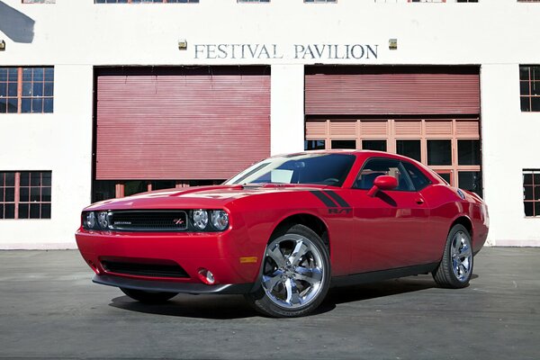 Красный автомобиль dodge challenger у здания