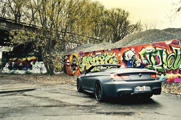 Black convertible and graffiti on the wall