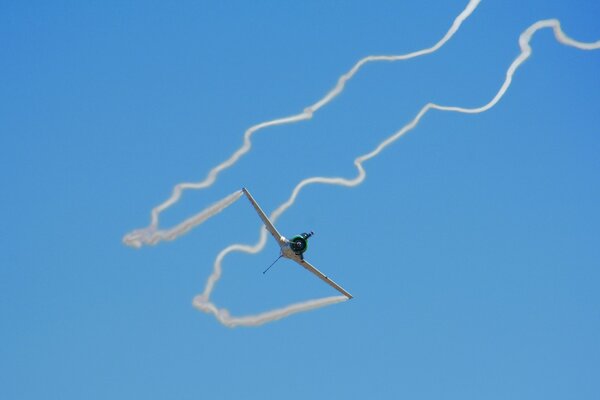 The plane leaves white intricate traces in the blue sky