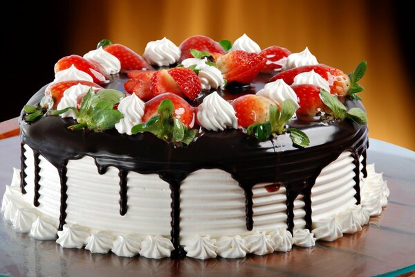 Birthday cake with chocolate icing, cream, mint leaves and strawberries