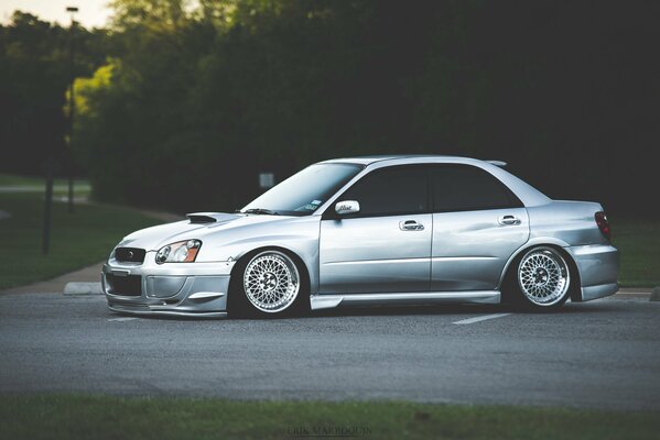 Silver Subaru on a background of trees