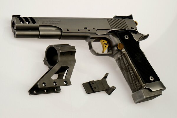 Disassembled pistol with a yellow trigger on a white background