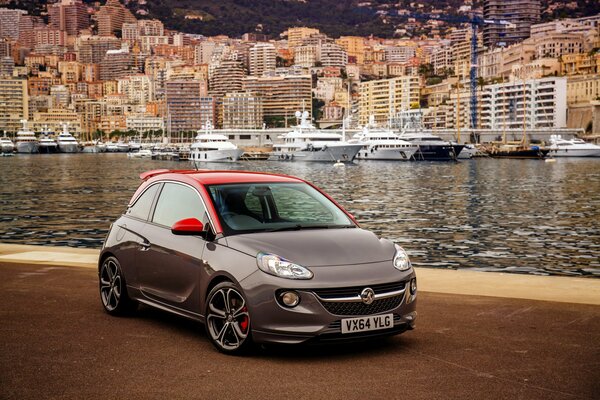 Opel Adam with a red roof on the background of yachts
