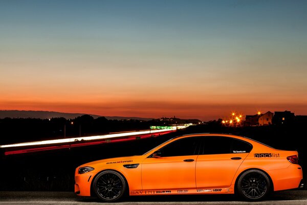 Оранжевое авто на фоне ночного города