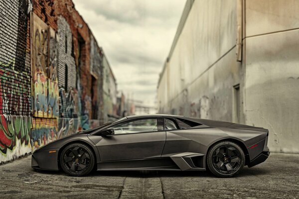 Black Lamborghini near the wall with graffiti