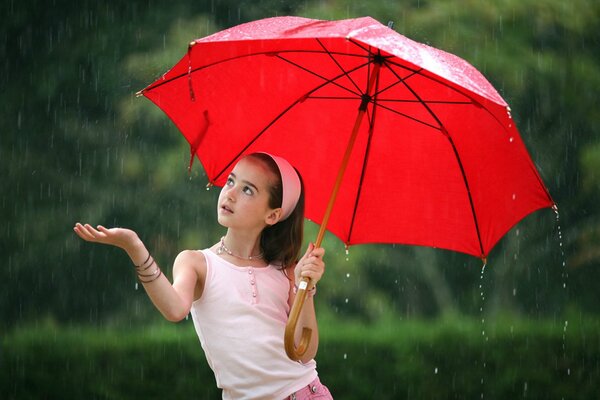 Mädchen im Regen mit einem roten Regenschirm