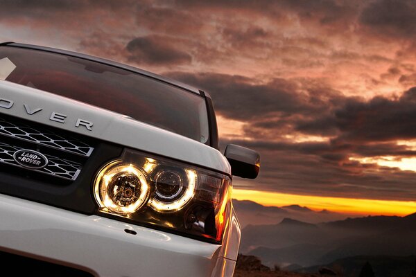 Coche blanco al atardecer de la montaña. Range Rover con nuevos faros