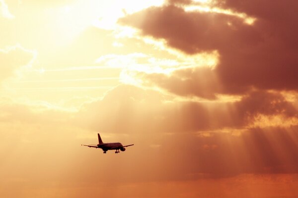 In the rays of the sun, an airplane flies through the clouds