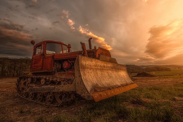 Bulldozer im Feld vor dem Hintergrund eines gewaltigen Himmels