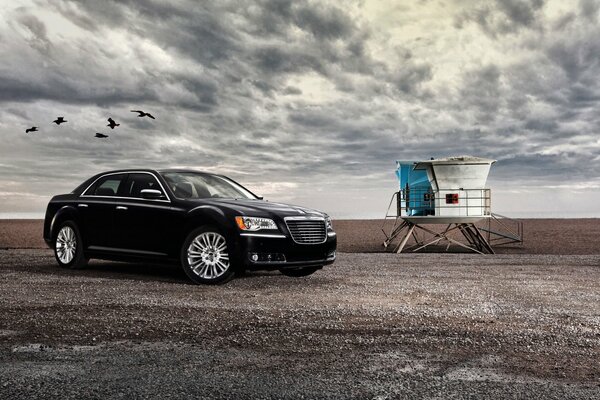 La voiture noire se trouve sous les nuages et devant cette voiture voler les oiseaux