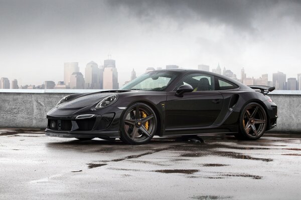 Porsche carrera 911 negro en el fondo de la ciudad