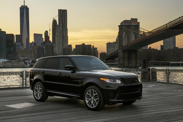 A black range rover is standing by the bridge