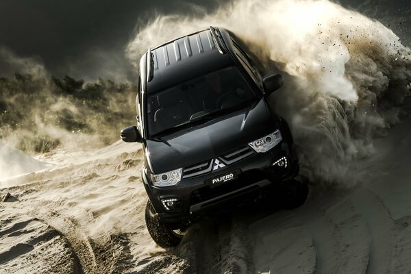 Black Mitsubishi Pajero on the sand in clouds of dust