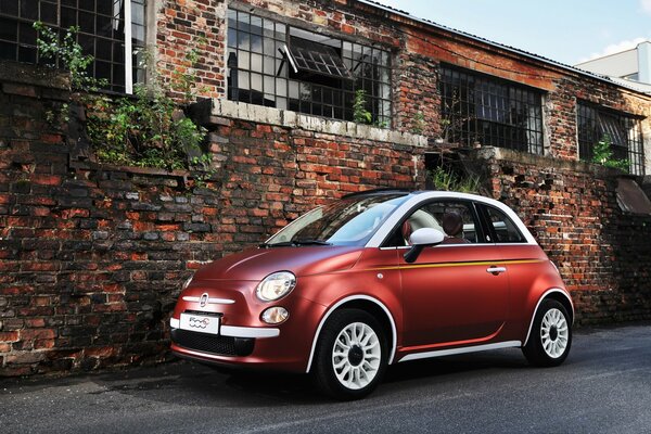 Voiture rouge debout brique contre le mur