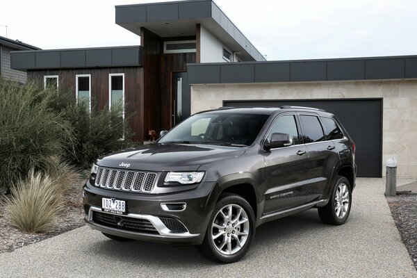 A black Jeep grand Cherokee is parked in front of the house