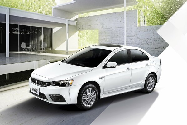 A white Mitsubishi Lancer and a beautiful house behind