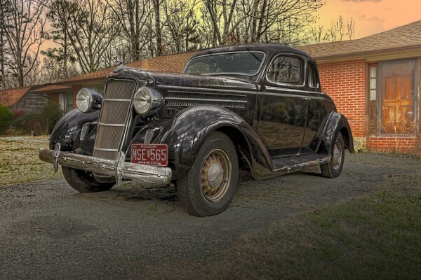 Un automóvil Dodge coupé retro de 1935 contra una casa de ladrillo rojo