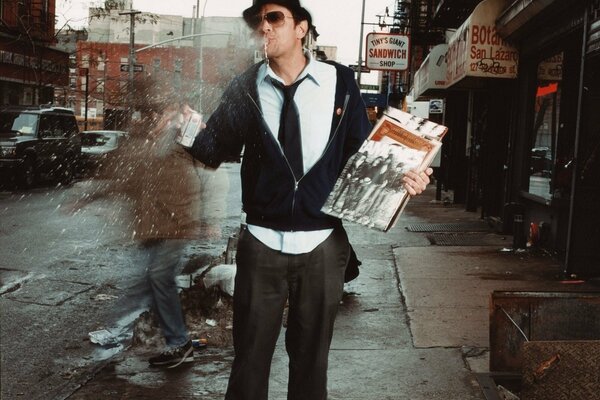 Johnny Nosksville de pie con un sombrero en la calle