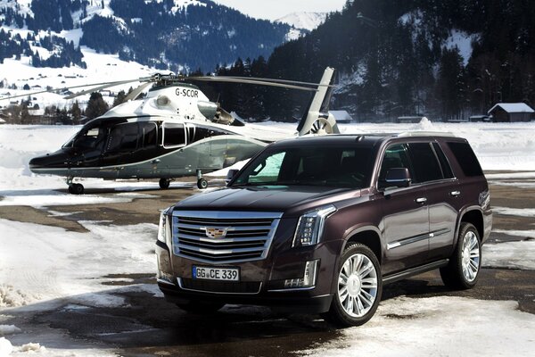 Cadillac et hélicoptère sur un paysage de montagne enneigé