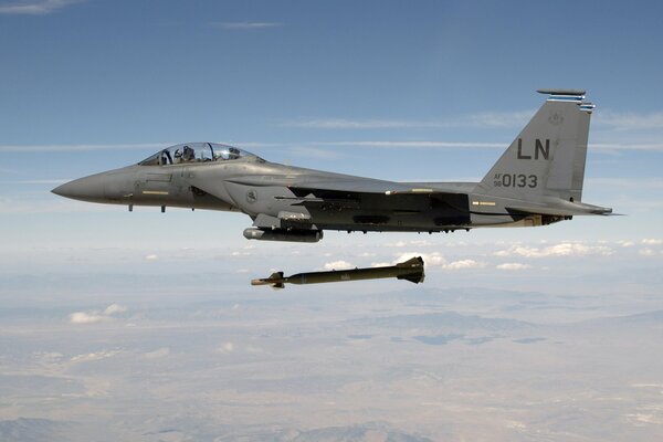 A military plane is captured in the air next to a rocket