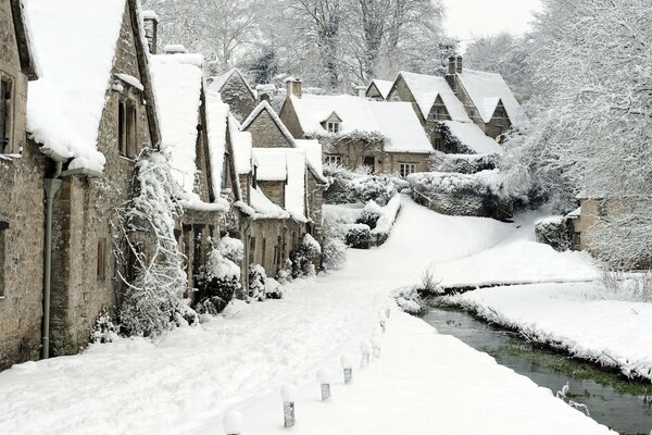 Casas nevadas de Inglaterra a lo largo de un arroyo