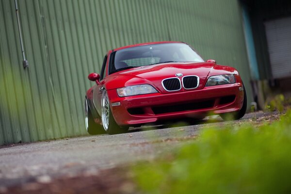 Czerwony widok BMW z przodu na tle ogrodzenia