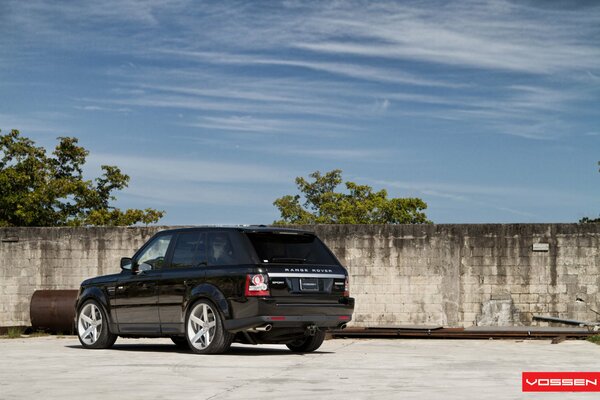 Range rover garé près de la vieille clôture et des tuyaux rouillés