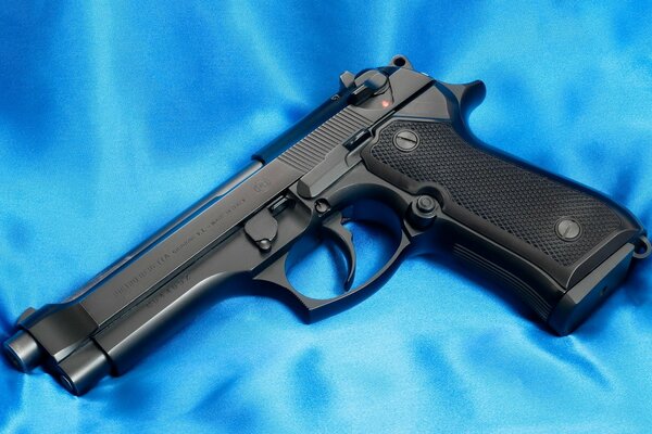 The beretta 92f pistol lies on a blue fabric