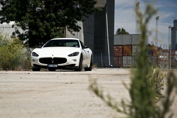 Maseratti blanco al lado de un camino de tierra