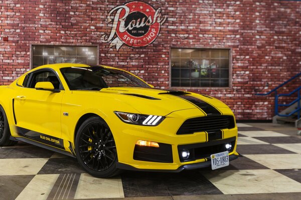 Giallo Ford Mustang su sfondo muro di mattoni