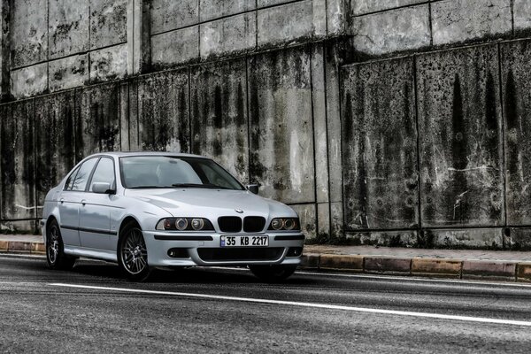 Un BMW 528i plateado se encuentra cerca de la pared