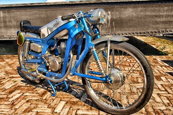 Blaues Vintage-Motorrad an der Pflastersteinpromenade