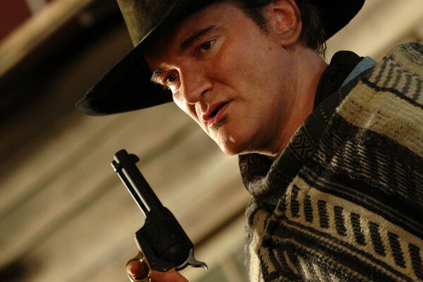 Quentin Tarantino trägt einen Hut mit einem Revolver in der Hand