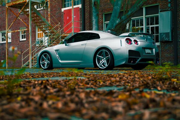 Silbernes Nissan-Auto auf Herbstlaub Hintergrund