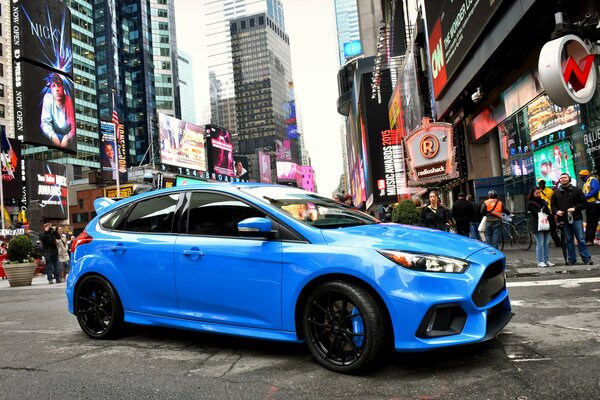 Ford azul en medio de una ciudad llena de gente