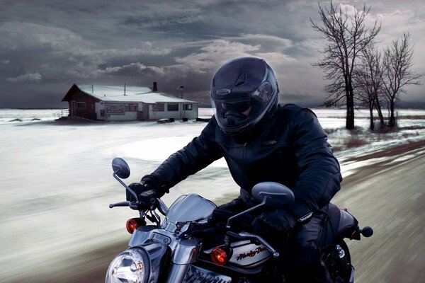 A guy in a helmet on a motorcycle against the background of a winter landscape