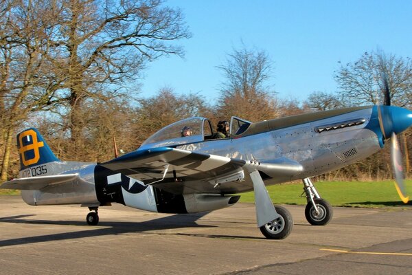 A single-seat American plane on the road against the background of trees