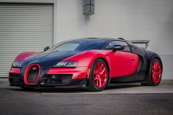 Red Bugatti Veyron rides slowly on the stone