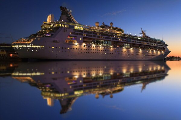 Kreuzfahrtschiff am Abend mit Lichtern und Reflexionen auf dem Wasser