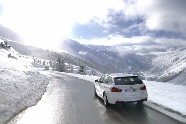 A white BMW is driving on a winter road