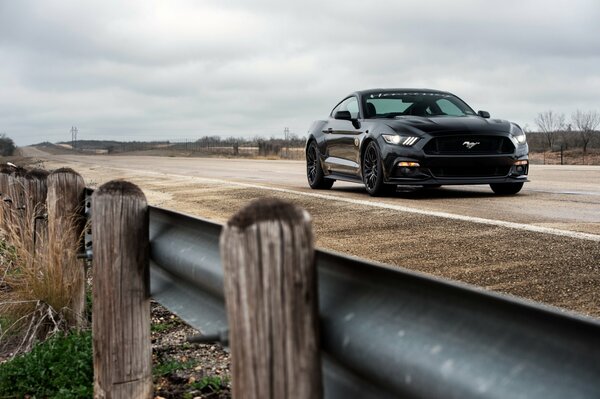 A black Ford car is driving on the road