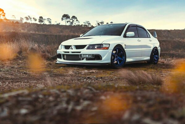 Foto del coche blanco al atardecer. Discos azules