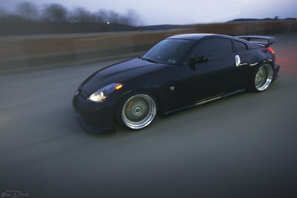 A dark sports car is driving at full speed on the highway