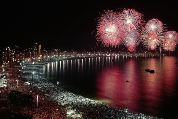 La costa del mar en la noche con las luces de la gran ciudad y el saludo