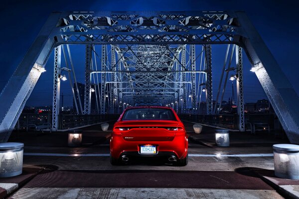 Красный автомобиль ночью стоит на мосту