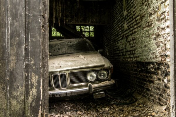 Arte retrò con una vecchia auto dimenticata in un garage di mattoni