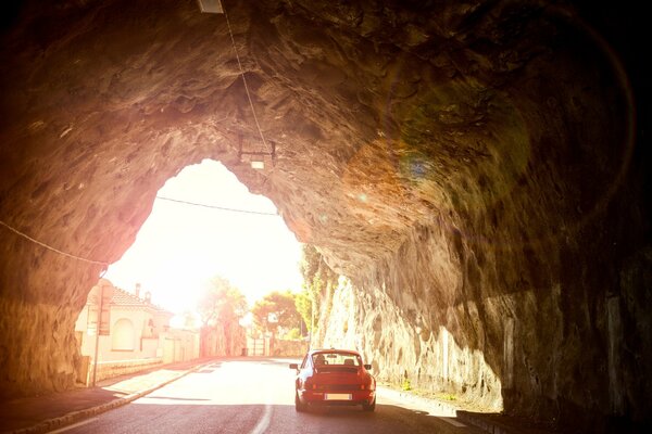 The Porsche leaves the tunnel in the rock on a sunny day